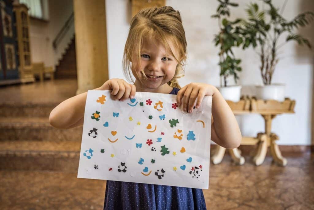 Ein Kind mit einem Blatt voller Sticker